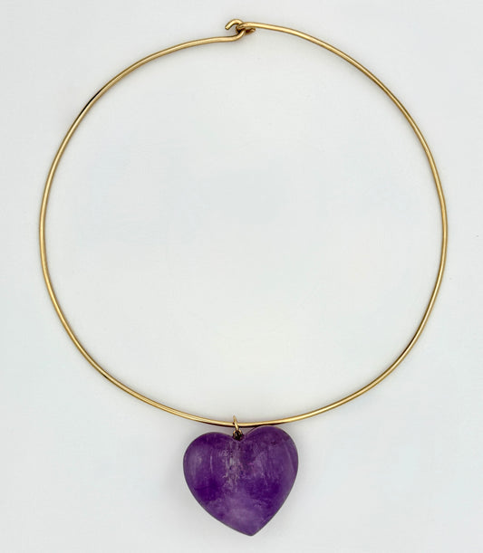 Gold necklace with a purple heart-shaped pendant on a white background