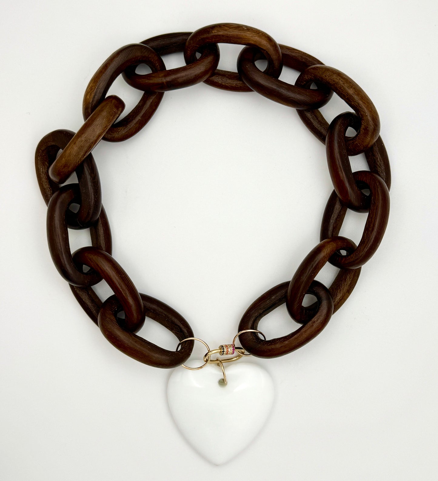 Brown chain necklace with a white heart pendant on a white background
