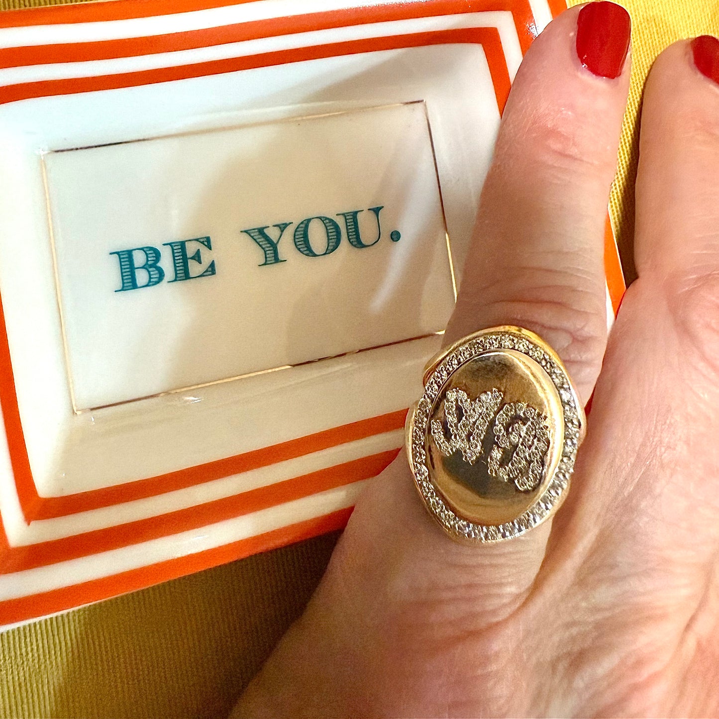 Gold ring with 'BE YOU' tray in the background