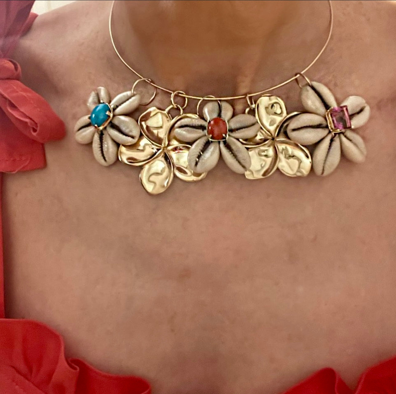 Necklace with floral designs and gemstones on a person wearing a red garment.