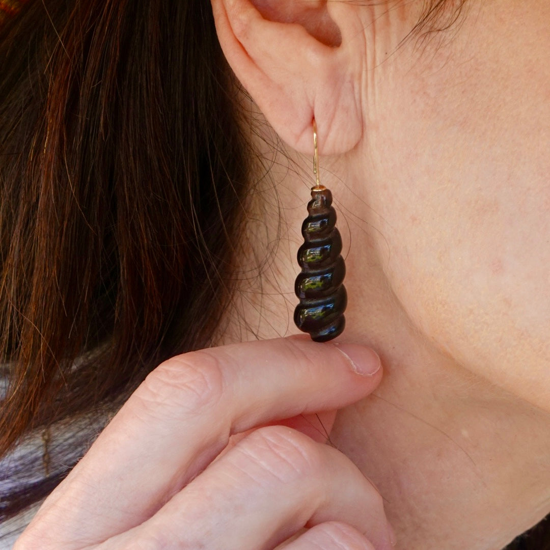 Close-up of a person wearing a dark brown beaded earring.