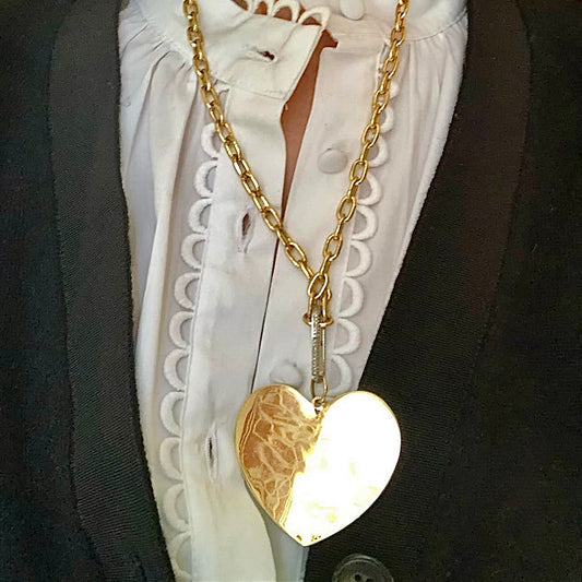 Gold heart-shaped pendant necklace on a white blouse with black jacket