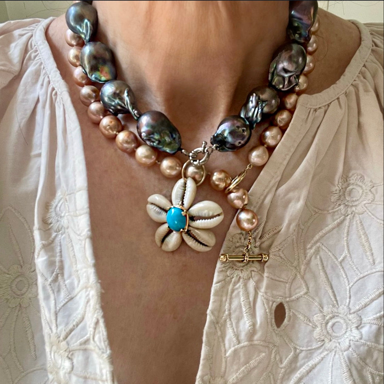 Necklace with pearls and a shell flower pendant on a textured white background