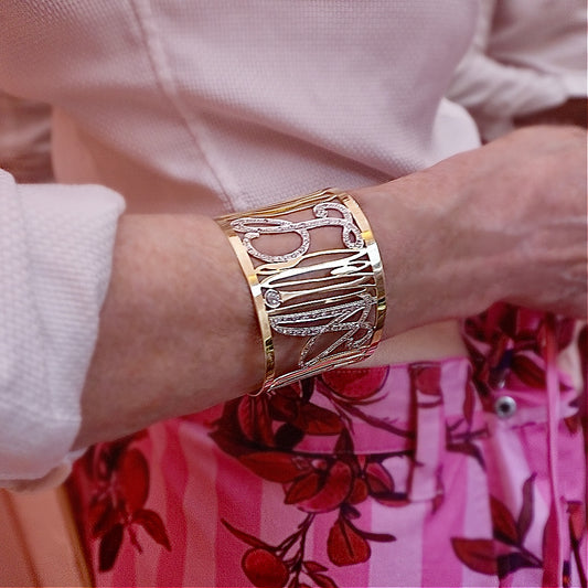 Gold bracelet on a wrist with a floral-patterned shirt in the background