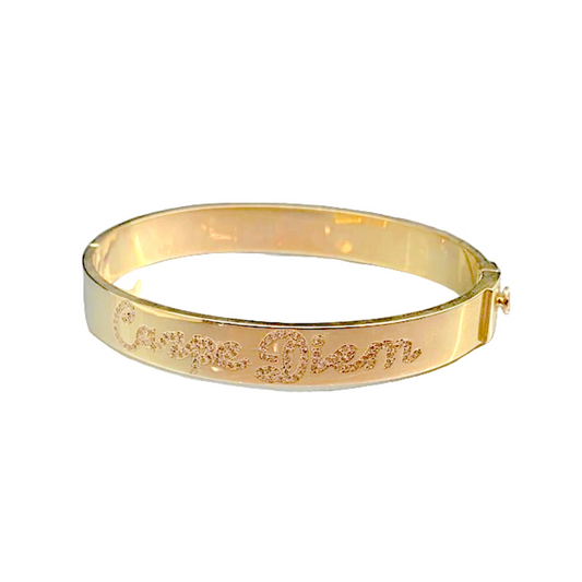 Gold bracelet with engraved text on a white background
