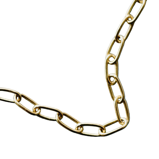 A close-up of a gold paperclip chain laid on a white background.