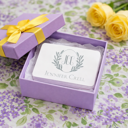 Purple gift box with yellow ribbon containing cards with 'Jennifer Creel' branding on a floral background.