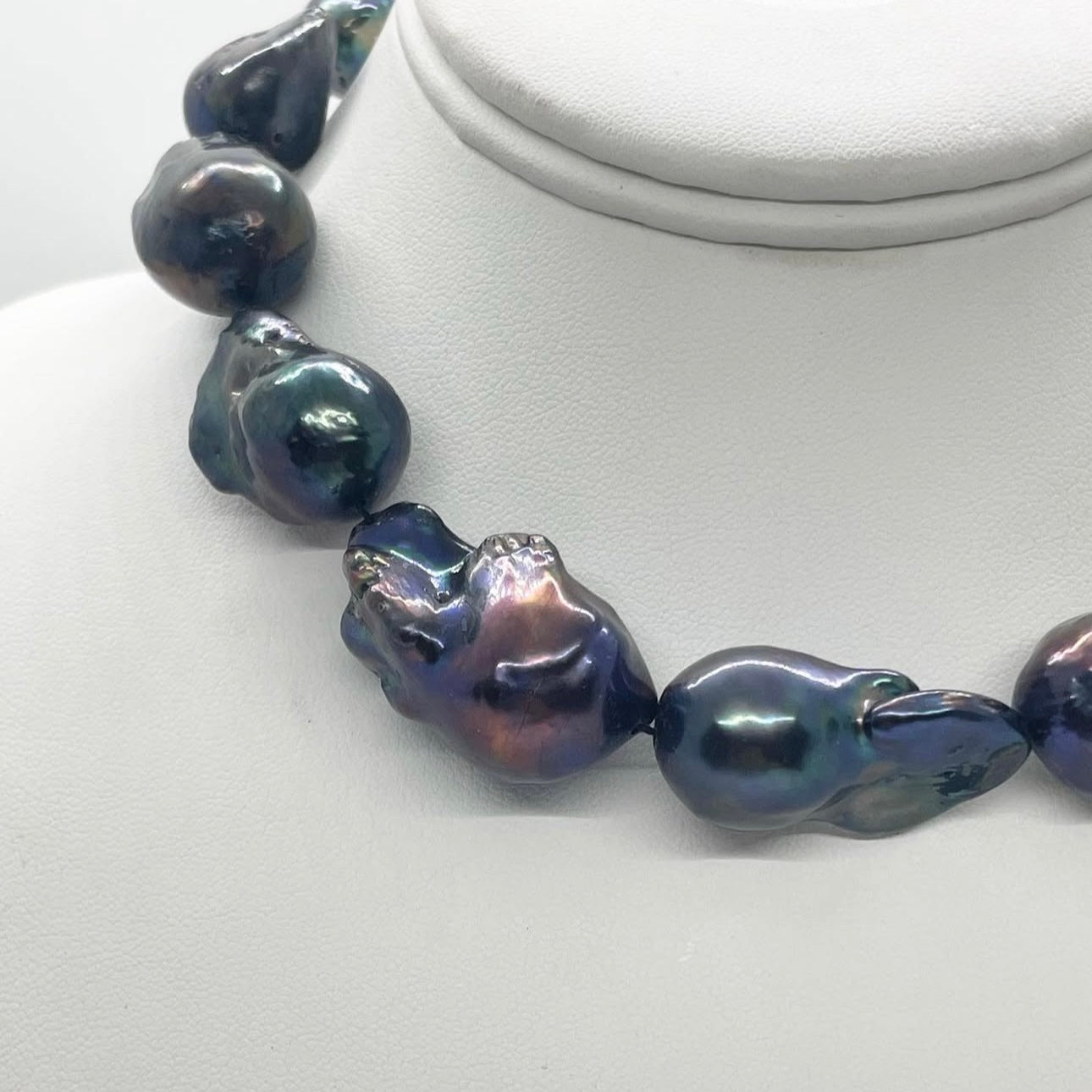 Necklace with large, dark-colored beads on a white mannequin.