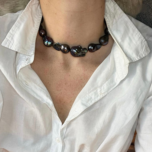 Person wearing a white shirt with a black beaded necklace
