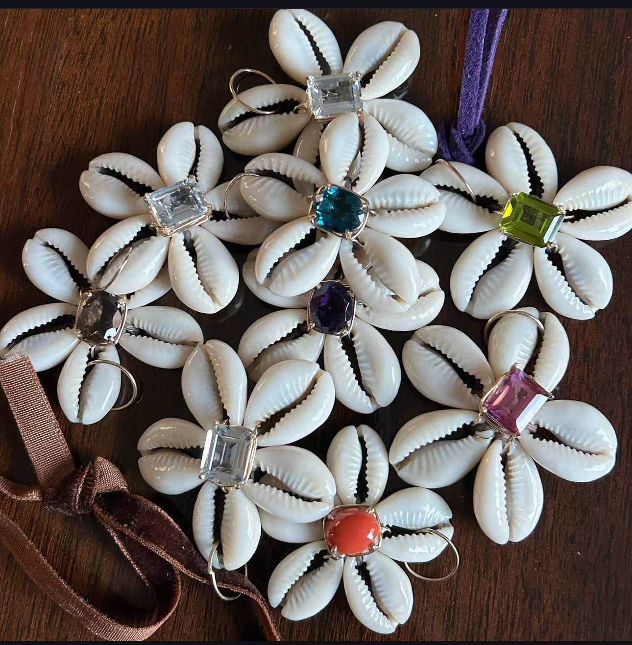 Cowrie shells with gemstone centers on a wooden surface