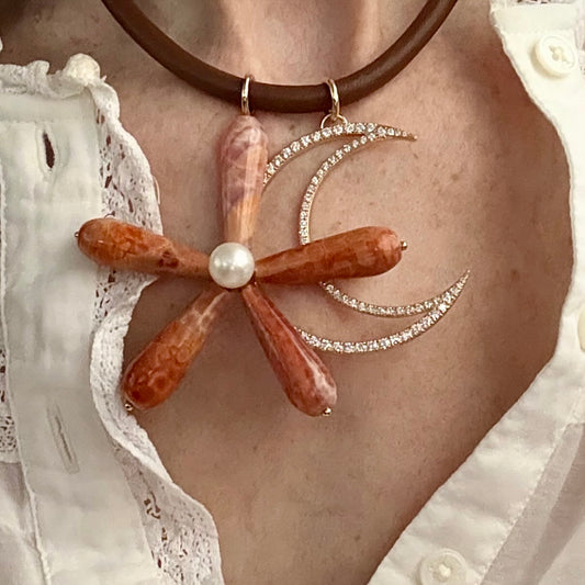 Necklace with a decorative pendant featuring a pearl on a person wearing a white lace garment.