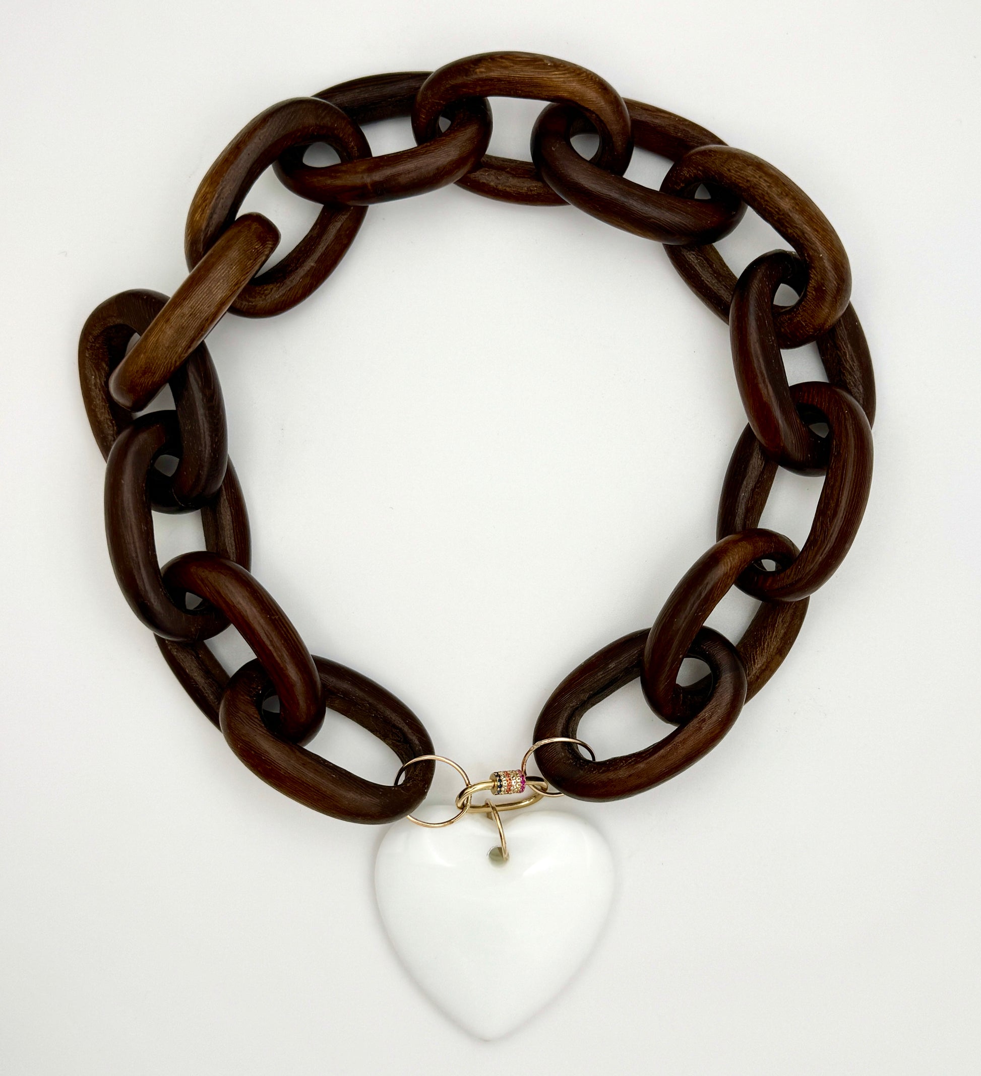 Brown chain necklace with a white heart pendant on a white background
