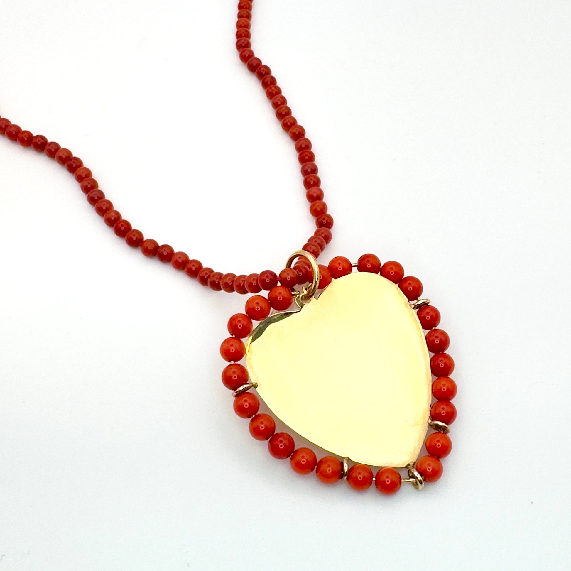 Necklace with a gold pendant and red beads on a white background