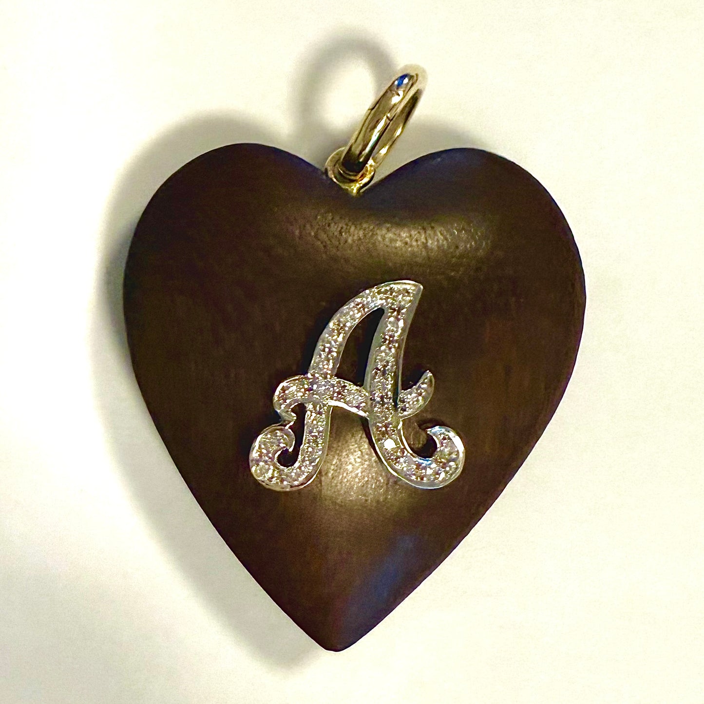 Heart-shaped pendant with a diamond-studded letter 'A' on a white background