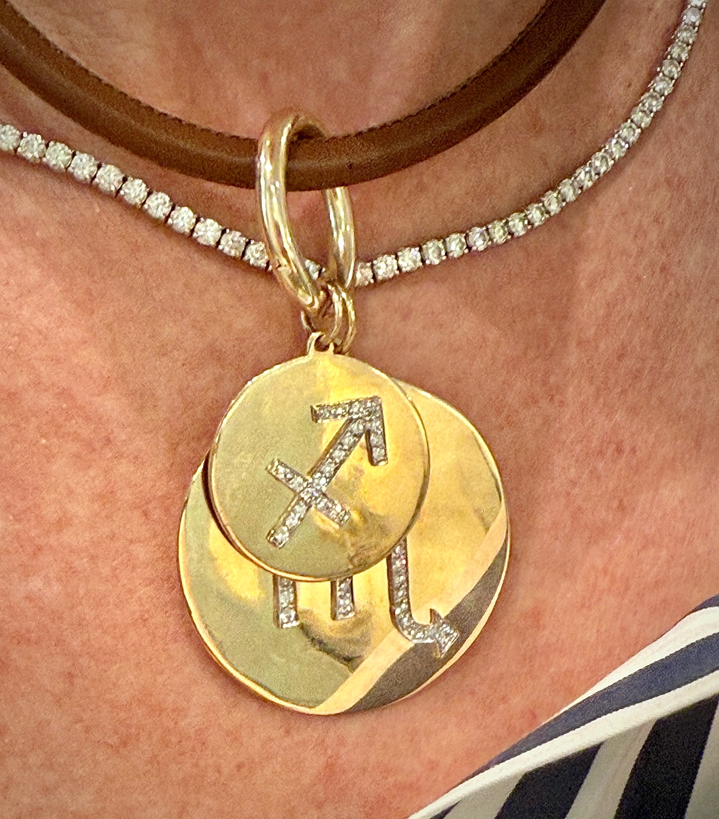 Gold pendant with zodiac symbol on a necklace against skin background