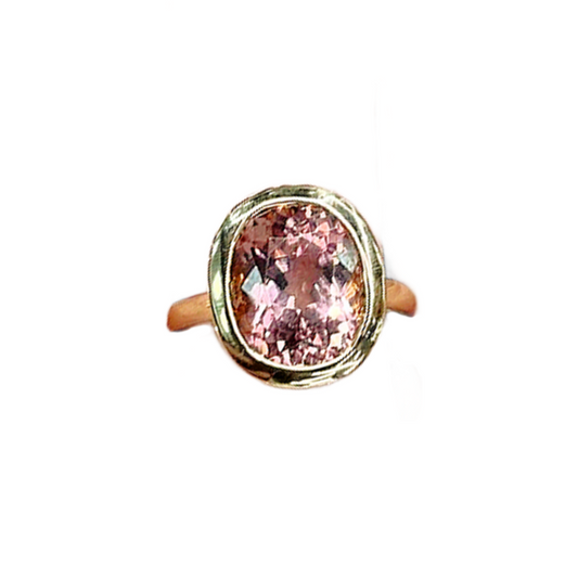 Ring with a pink gemstone and gold band on a white background