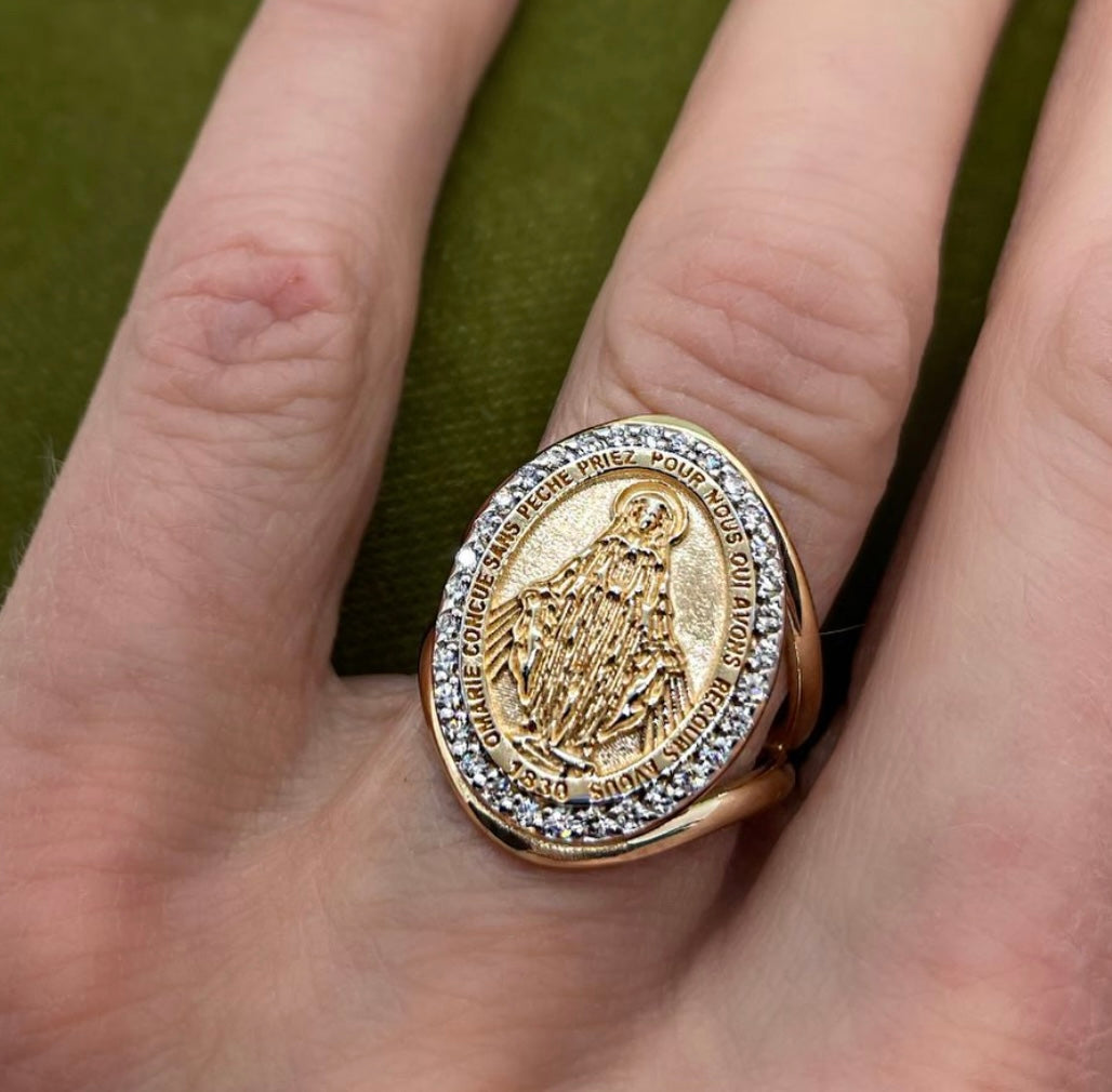 Gold ring with religious design on a person's finger