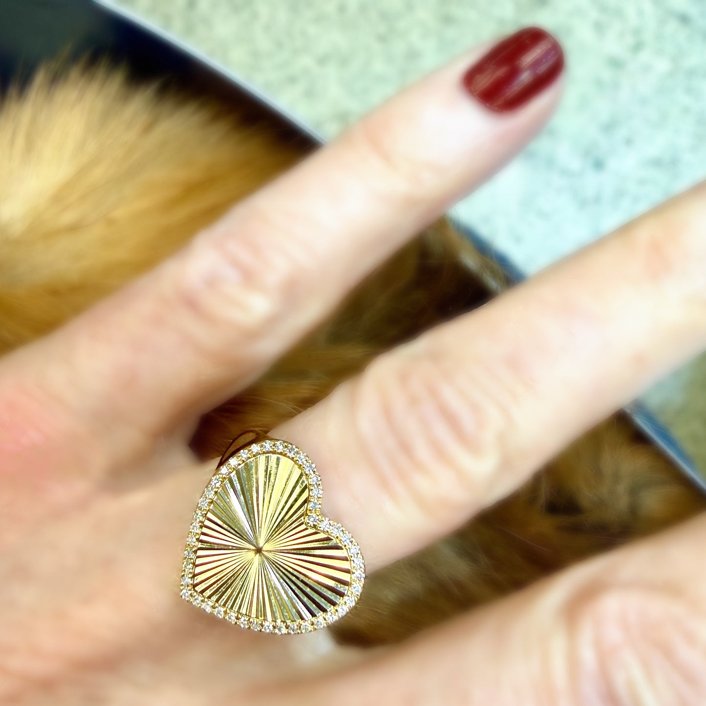 Gold ring with sunburst design on a finger