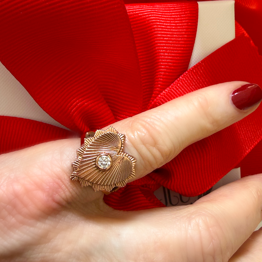 Gold ring with a diamond on a finger against a red ribbon background