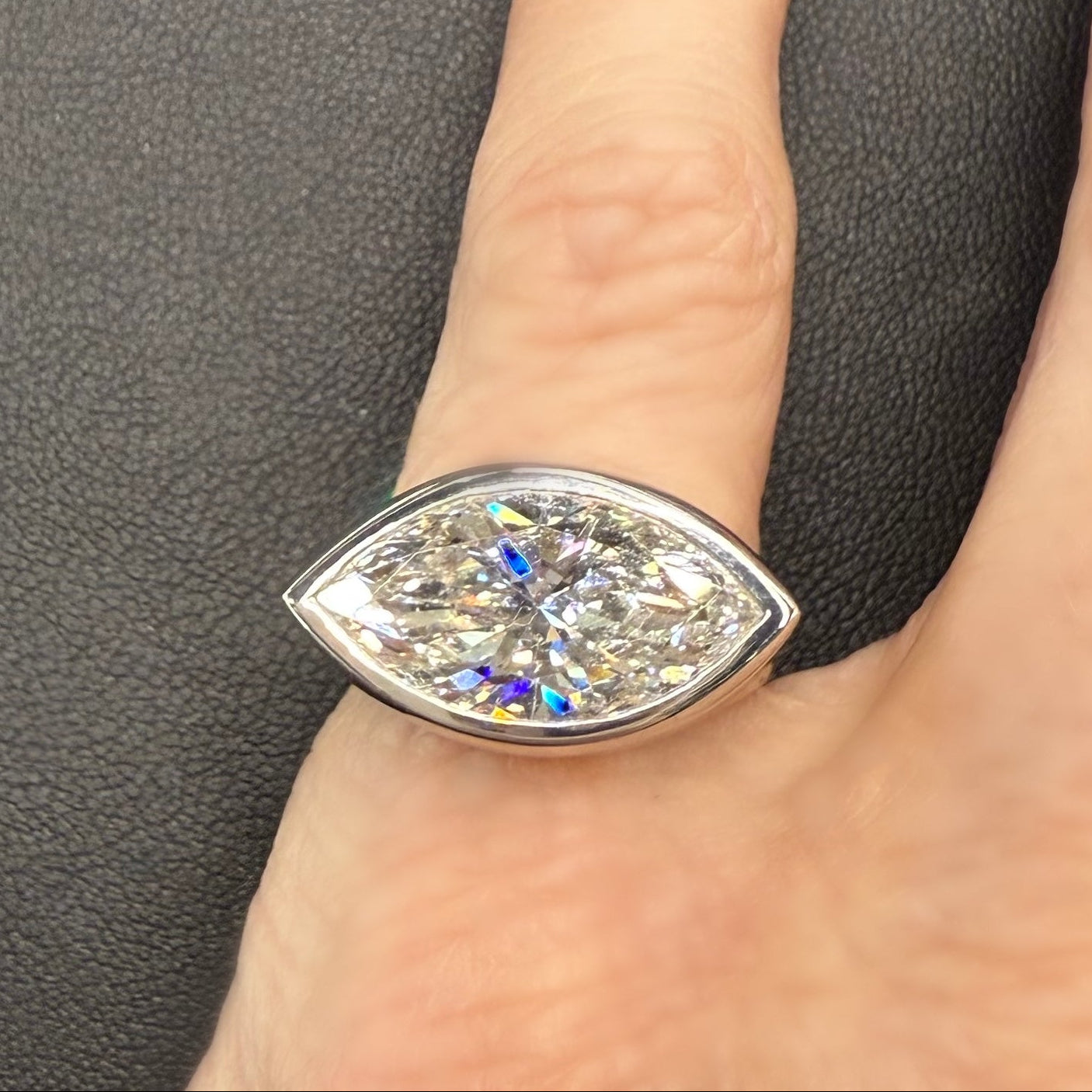 Pear-shaped diamond ring on a finger against a gray background