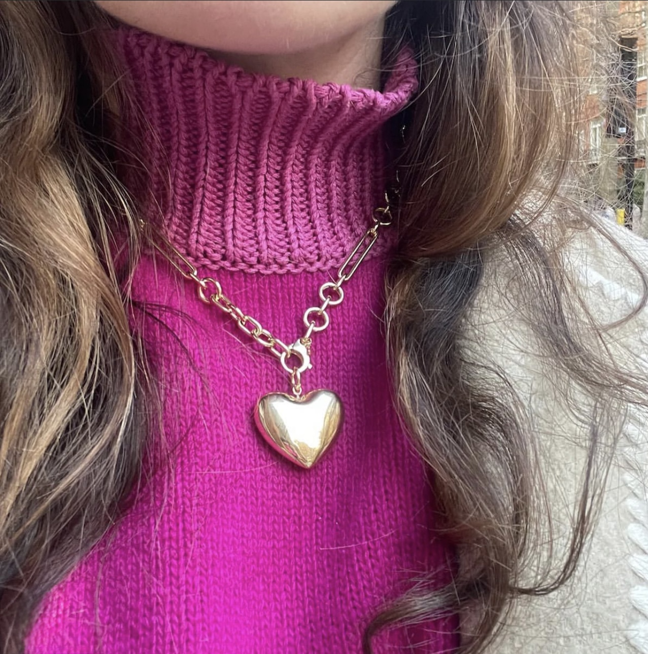 Heart shaped necklace on a person wearing a pink sweater. 