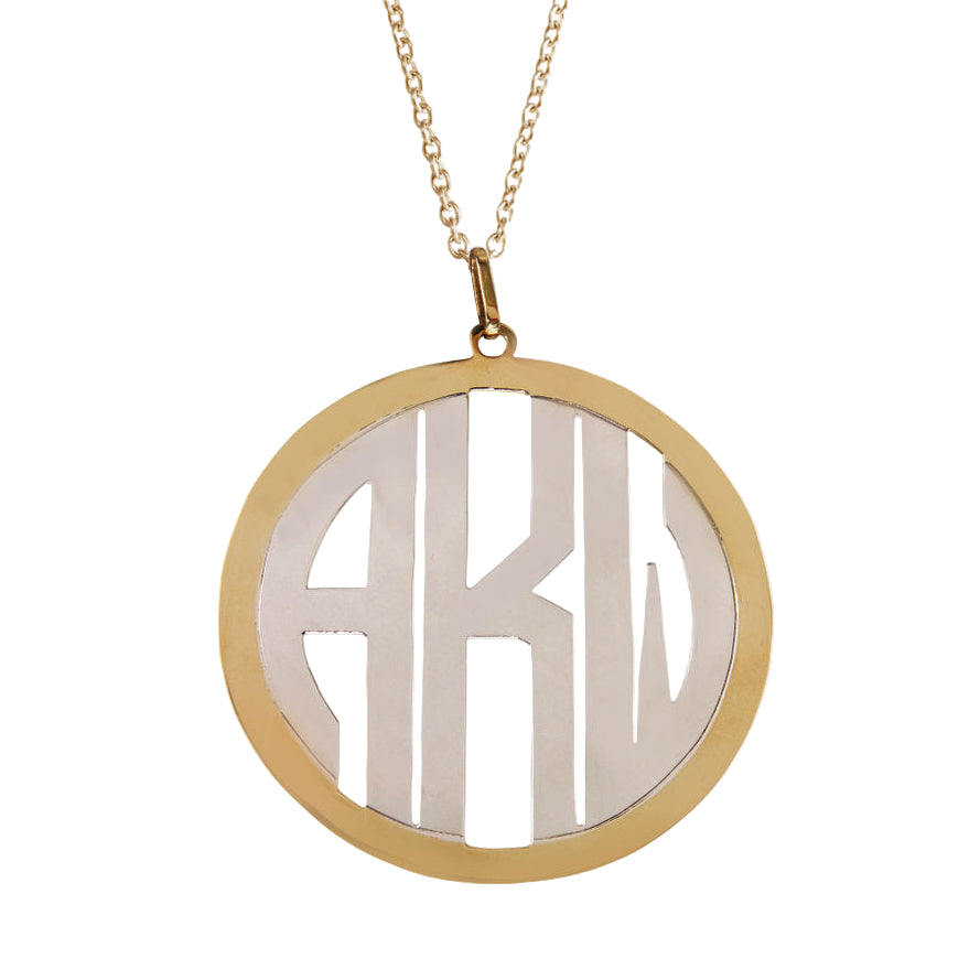 A 14kt yellow gold frame with a 14kt white gold monogram 2” pendant with block lettering.