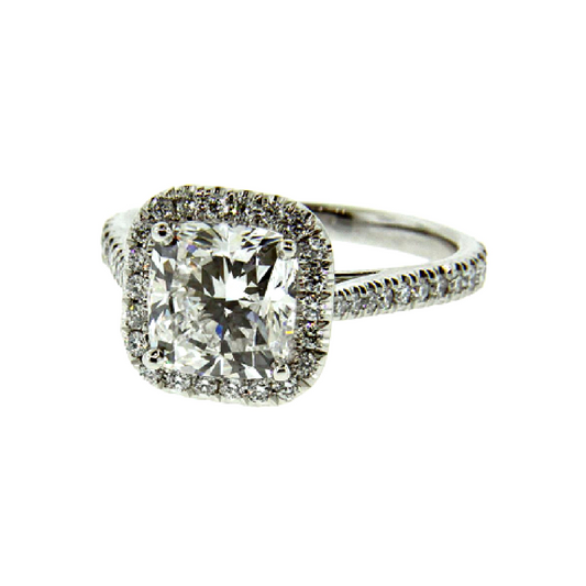 A cushion cut diamond halo engagement ring with a platinum setting, encrusted with smaller diamonds along the band.