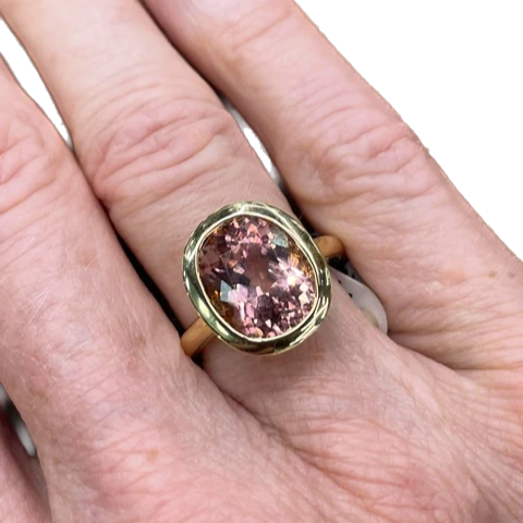 A hand wearing an 18k gold candy stone ring with tourmaline stones.