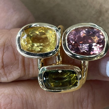 Gold ring with three colorful gemstones on a hand